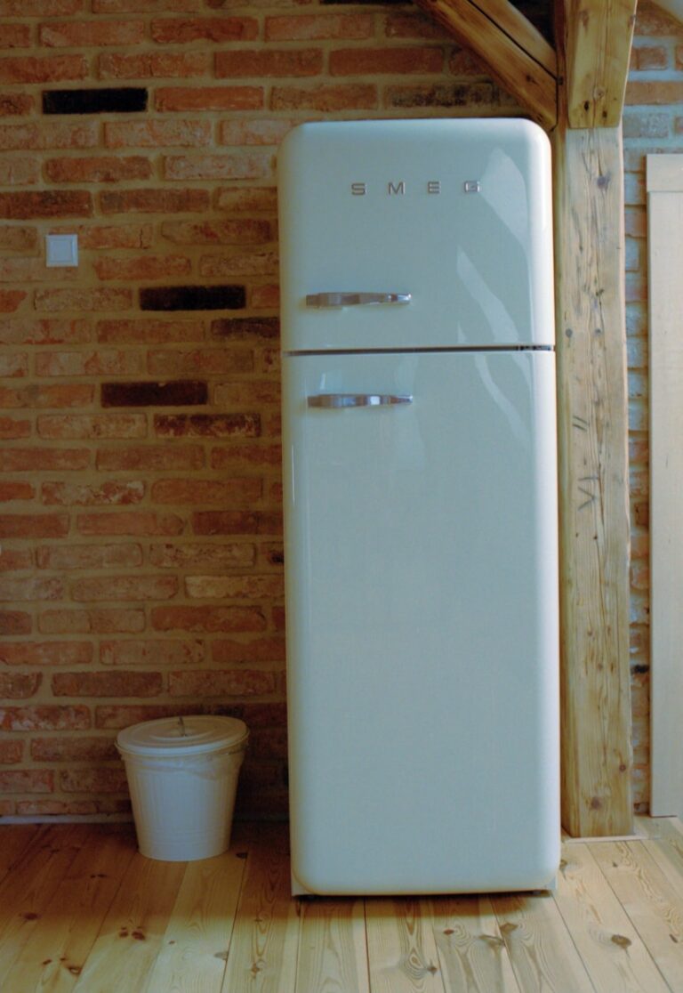 A white refrigerator freezer sitting on top of a wooden floor