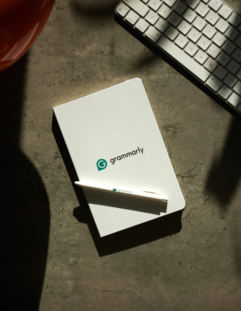 Grammarly notebook, pen, and keyboard on a desk.