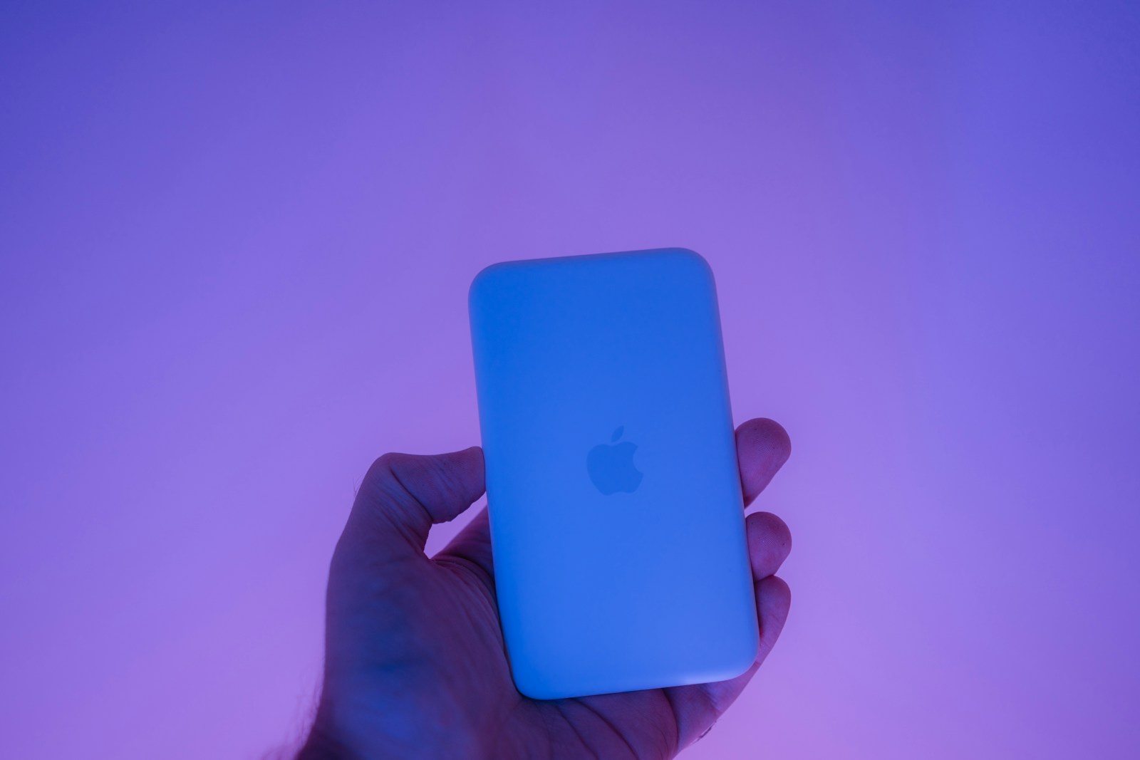 Hand holding a white apple magsafe charger